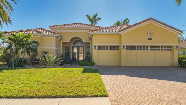 mediterranean / spanish-style house with french doors, a garage, and a front lawn