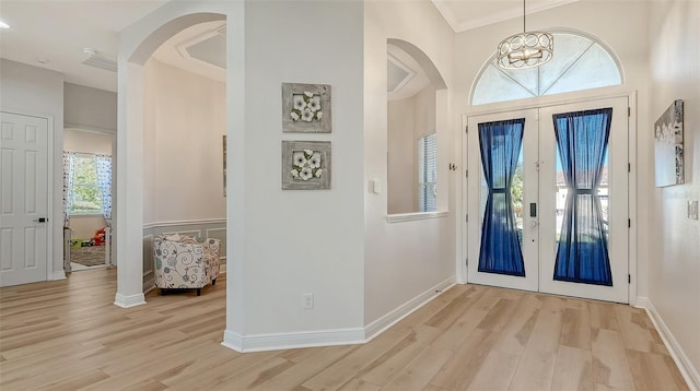 entrance foyer with french doors, light hardwood / wood-style floors, crown molding, and a healthy amount of sunlight