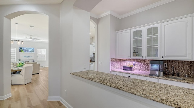 kitchen with white cabinetry, sink, ceiling fan, backsplash, and light wood-type flooring