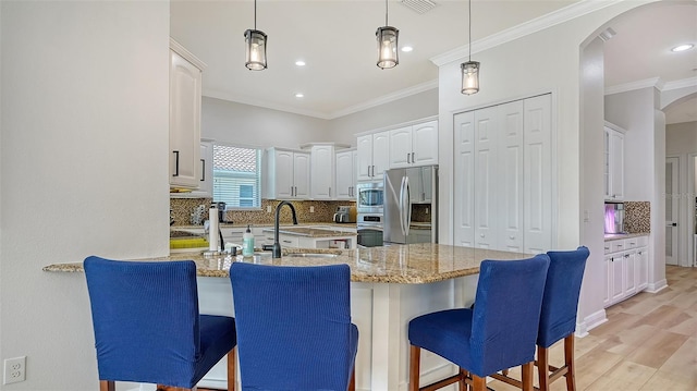 kitchen featuring light hardwood / wood-style flooring, light stone countertops, white cabinetry, kitchen peninsula, and stainless steel appliances