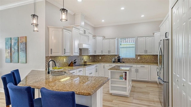 kitchen with stainless steel refrigerator, kitchen peninsula, white cabinets, and a kitchen island