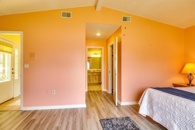 bedroom featuring connected bathroom, lofted ceiling with beams, and light hardwood / wood-style floors