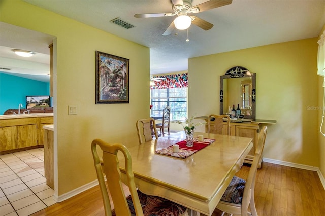 dining room featuring ceiling fan, sink, light hardwood / wood-style floors, and a textured ceiling