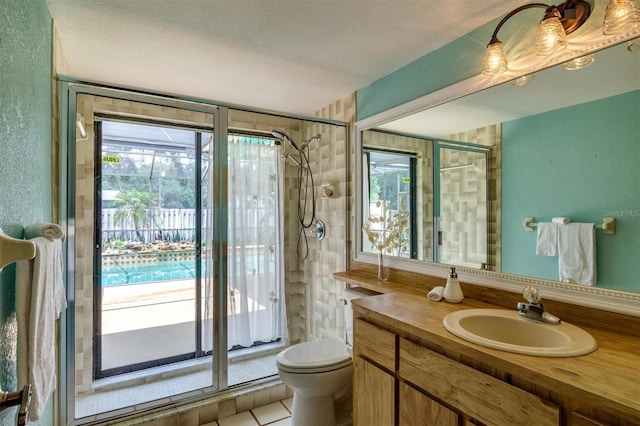 bathroom featuring tile patterned floors, a textured ceiling, vanity, tiled shower, and toilet