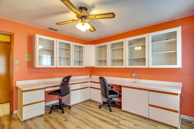 home office with built in desk, light hardwood / wood-style flooring, and ceiling fan