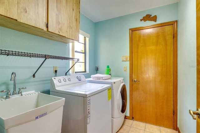 laundry room featuring washing machine and clothes dryer, sink, light tile patterned floors, and cabinets