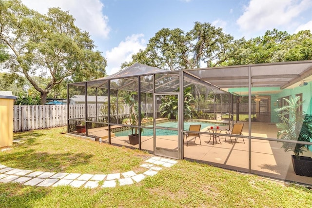 view of pool with a patio, glass enclosure, ceiling fan, and a lawn