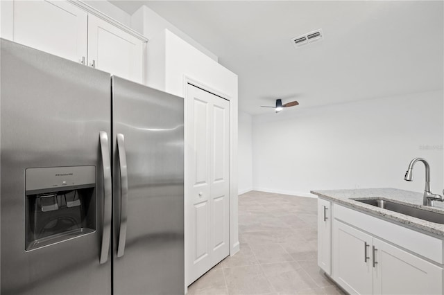 kitchen featuring stainless steel refrigerator with ice dispenser, light stone counters, ceiling fan, sink, and white cabinets