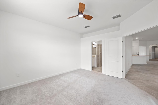 unfurnished bedroom featuring ensuite bathroom, ceiling fan, and light colored carpet