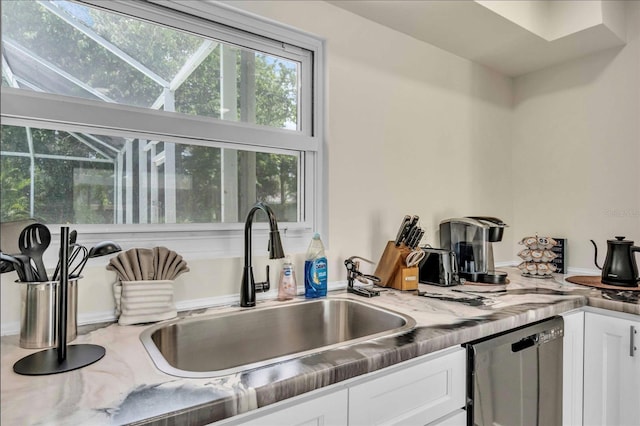 kitchen with dishwasher, white cabinetry, and sink