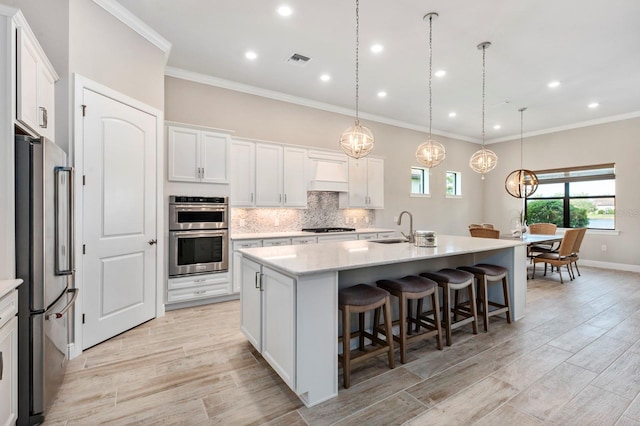 kitchen featuring pendant lighting, sink, an island with sink, white cabinetry, and stainless steel appliances