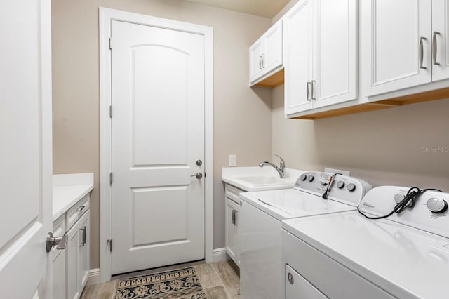 laundry room featuring light hardwood / wood-style floors, cabinets, independent washer and dryer, and sink