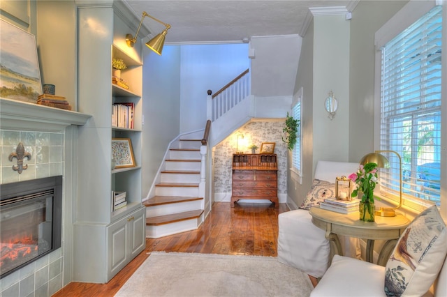 stairs with a fireplace, ornamental molding, a textured ceiling, and hardwood / wood-style flooring