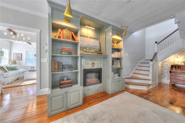 interior space featuring wood-type flooring, a textured ceiling, ornamental molding, and built in shelves