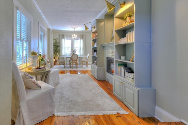 interior space with crown molding, light hardwood / wood-style floors, a textured ceiling, and a notable chandelier