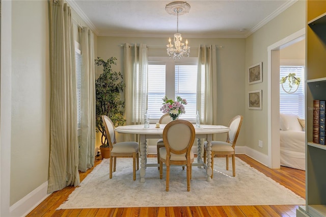 dining room with light hardwood / wood-style floors, crown molding, and a notable chandelier