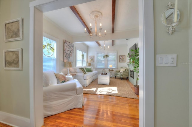 living room featuring beam ceiling, ornamental molding, a notable chandelier, and hardwood / wood-style flooring