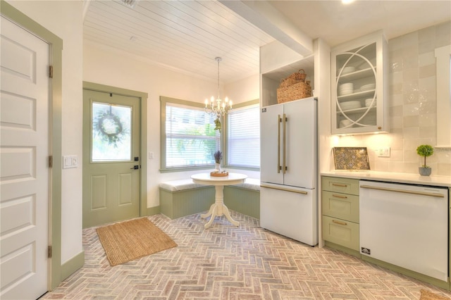 kitchen featuring backsplash, white appliances, pendant lighting, a notable chandelier, and green cabinets