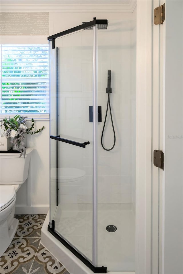 bathroom featuring tile patterned flooring, toilet, a shower with door, and crown molding