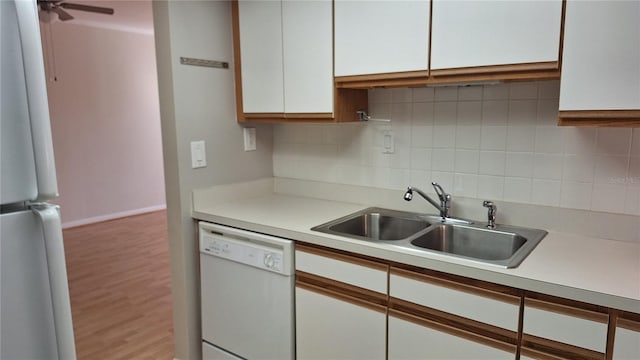 kitchen featuring white appliances, white cabinets, sink, decorative backsplash, and light wood-type flooring