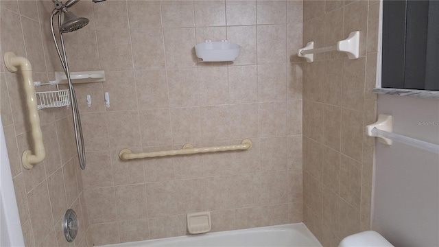 bathroom featuring toilet and tiled shower / bath