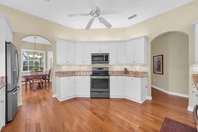 kitchen with ceiling fan with notable chandelier, hanging light fixtures, light hardwood / wood-style floors, white cabinetry, and stainless steel appliances