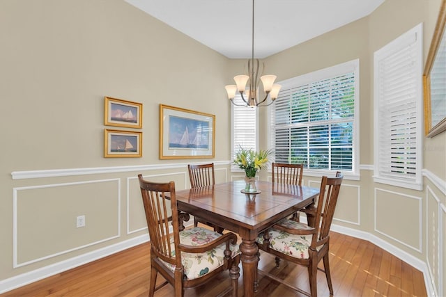 dining area with wood-type flooring and an inviting chandelier