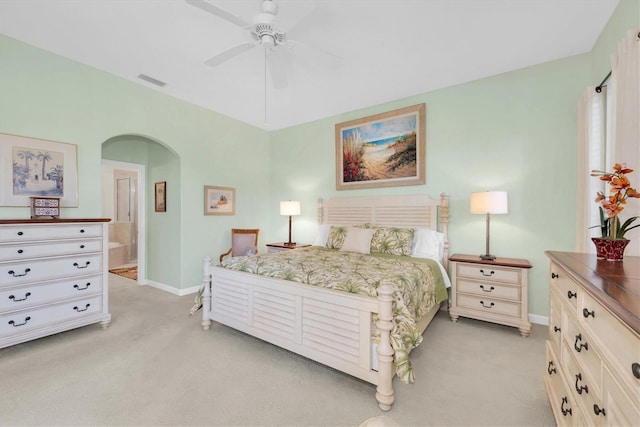 bedroom featuring ceiling fan, ensuite bathroom, and light colored carpet