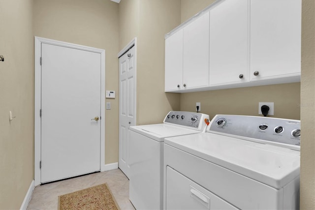 laundry room with washer and clothes dryer, light tile patterned floors, and cabinets