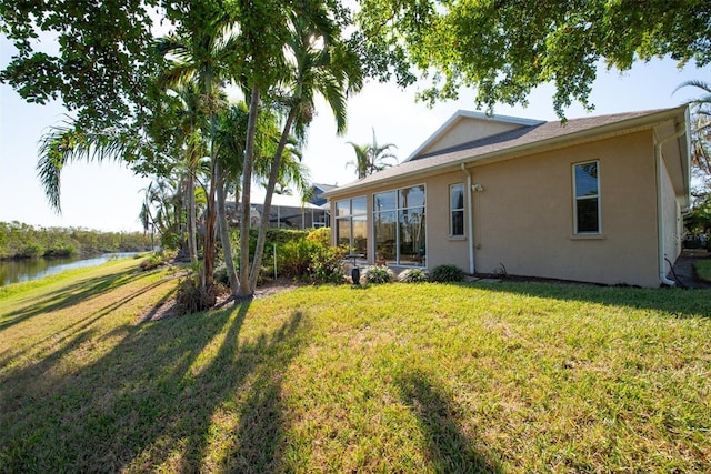 view of yard with a sunroom and a water view