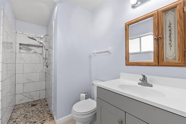 bathroom featuring vanity, toilet, and tiled shower