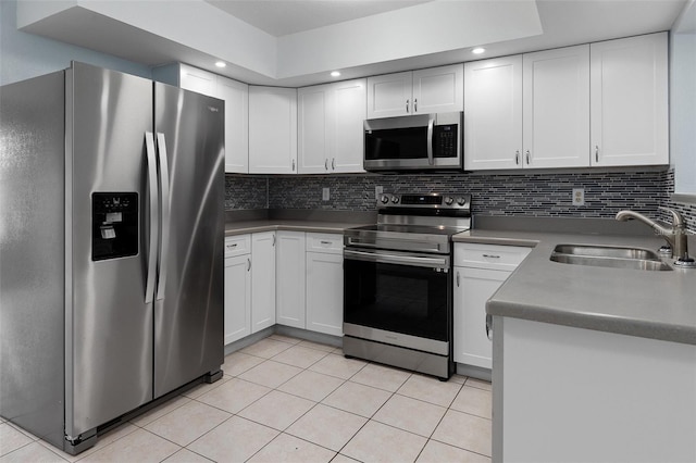 kitchen with tasteful backsplash, sink, white cabinets, and appliances with stainless steel finishes