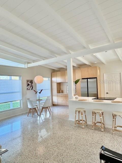 kitchen featuring beamed ceiling, light brown cabinets, wood ceiling, and stainless steel refrigerator