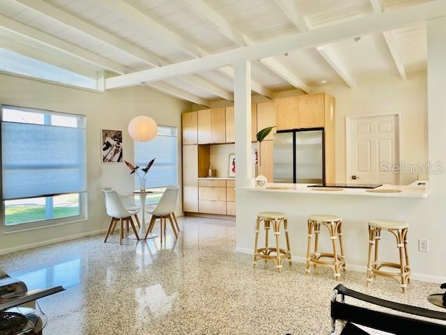 kitchen with lofted ceiling with beams, stainless steel fridge, and light brown cabinets