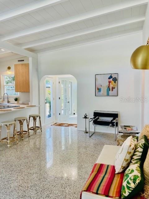 living room featuring beam ceiling, wood ceiling, a wealth of natural light, and sink