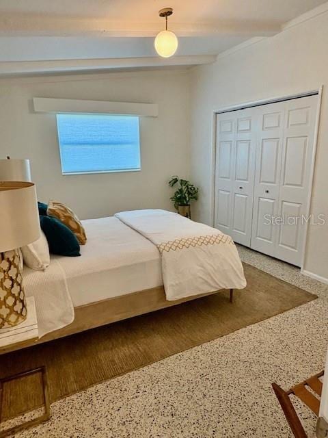 bedroom featuring beam ceiling and a closet