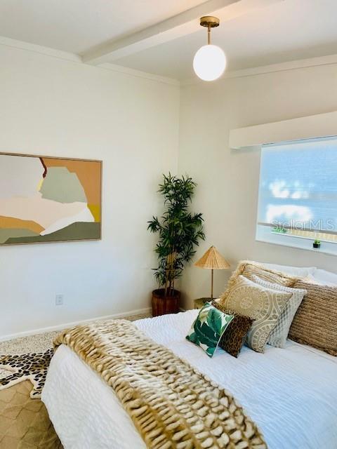 bedroom with beamed ceiling and ornamental molding