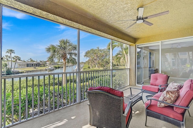 sunroom / solarium with ceiling fan and a water view