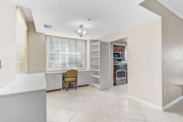 office area featuring light tile patterned floors, built in desk, and a textured ceiling