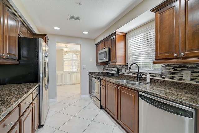 kitchen with dark stone countertops, stainless steel appliances, a healthy amount of sunlight, and sink