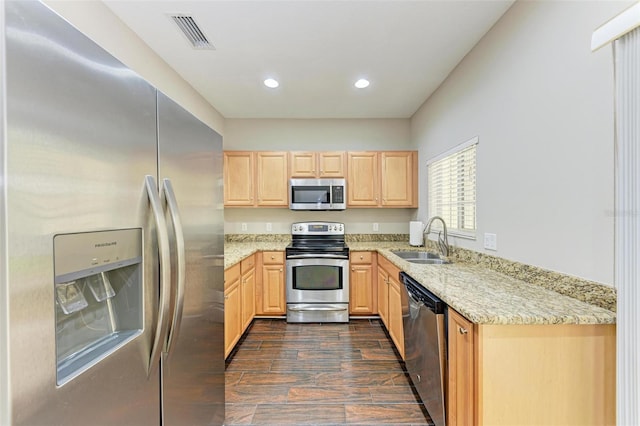 kitchen featuring light stone countertops, light brown cabinetry, stainless steel appliances, and sink