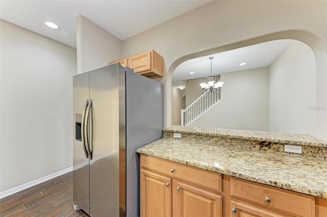 kitchen with stainless steel fridge, light stone countertops, decorative light fixtures, and an inviting chandelier