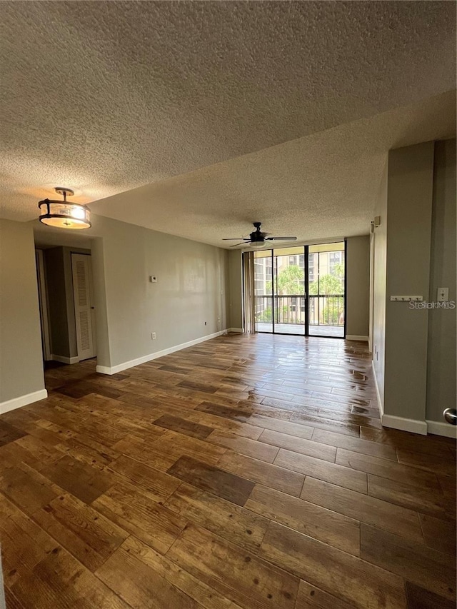 empty room with a textured ceiling, dark hardwood / wood-style flooring, and ceiling fan