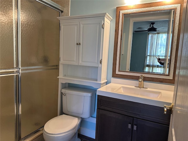 bathroom with ceiling fan, vanity, a shower with shower door, and toilet