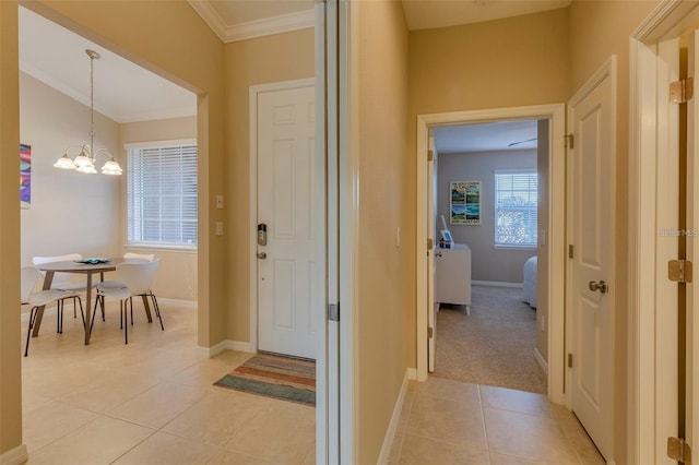 corridor featuring crown molding, a notable chandelier, and light tile patterned floors