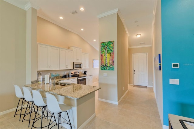 kitchen featuring a breakfast bar, appliances with stainless steel finishes, white cabinetry, light stone counters, and kitchen peninsula