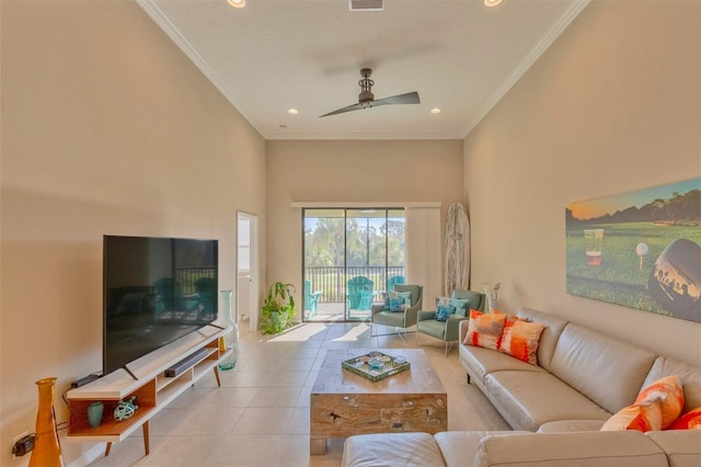 living room with ceiling fan, ornamental molding, a high ceiling, and light tile patterned floors