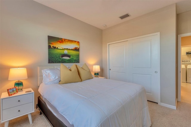 carpeted bedroom featuring washing machine and dryer and a closet