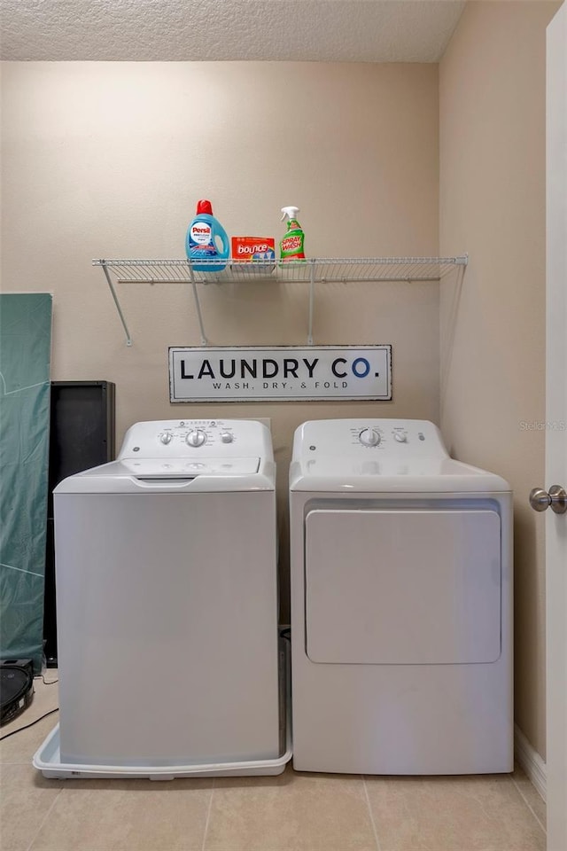 laundry area featuring light tile patterned floors, independent washer and dryer, and a textured ceiling