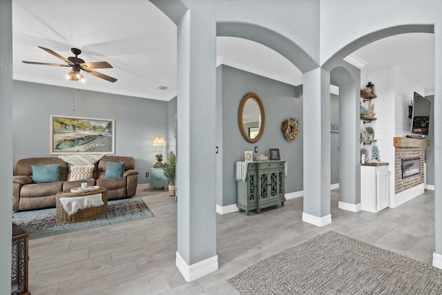 living room with ceiling fan, a fireplace, and ornamental molding